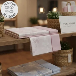 Primer plano del juego de 3 sábanas ABECÉ modelo ALINA 21703, con estampado floral y lunares, dobladas en una estantería. Se aprecia el detalle de la composición: 48% algodón, 52% poliéster. Disponible para camas de 90, 105, 135 y 150cm.